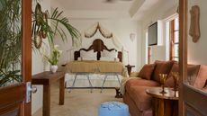 A suite bedroom at Raes Guesthouses with a tasseled bed canopy and brown details