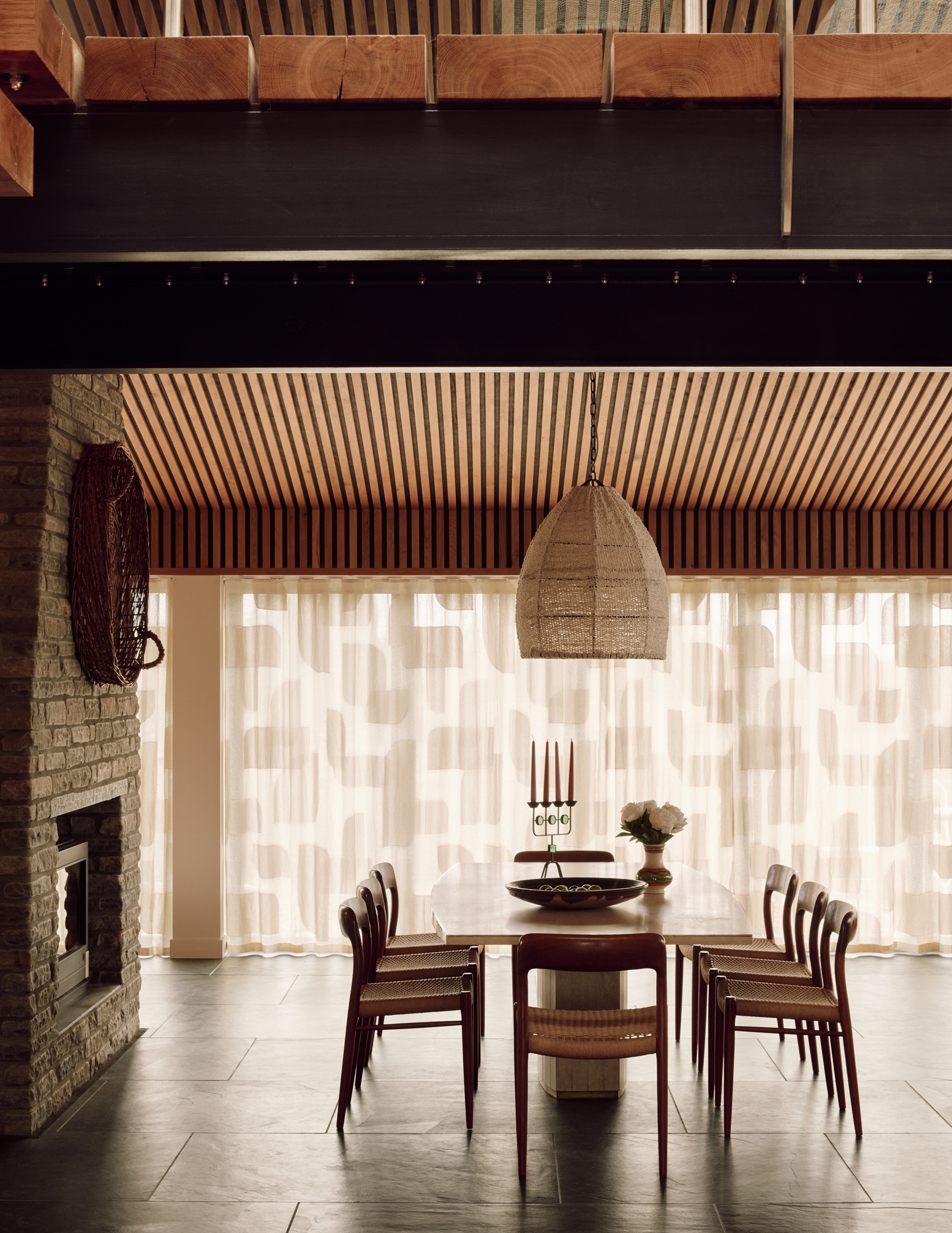 a dining room in a lofty modern home with sheer curtains with patterned shapes on them
