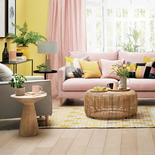 living area with yellow wall and pink curtain and pink sofa and wooden floor and armchair