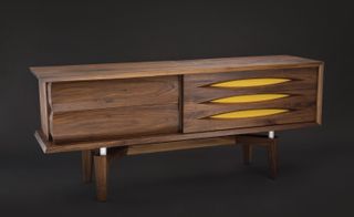 Low cabinet of dark wood with sliding front door and yellow detailing
