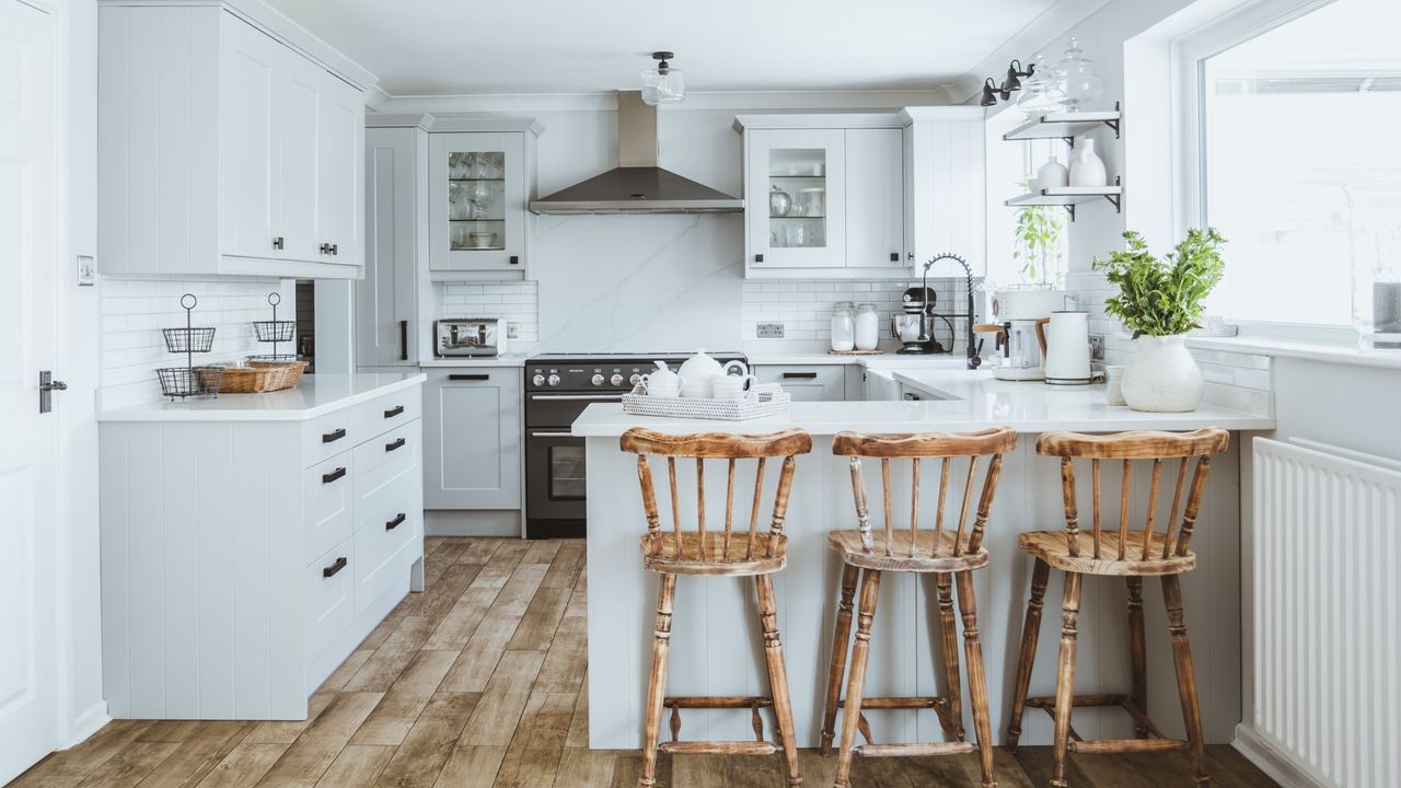 Pale blue kitchen cabinets in G-shape layout with wooden stools