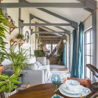 room with wooden logs and grey sofa and plant pots