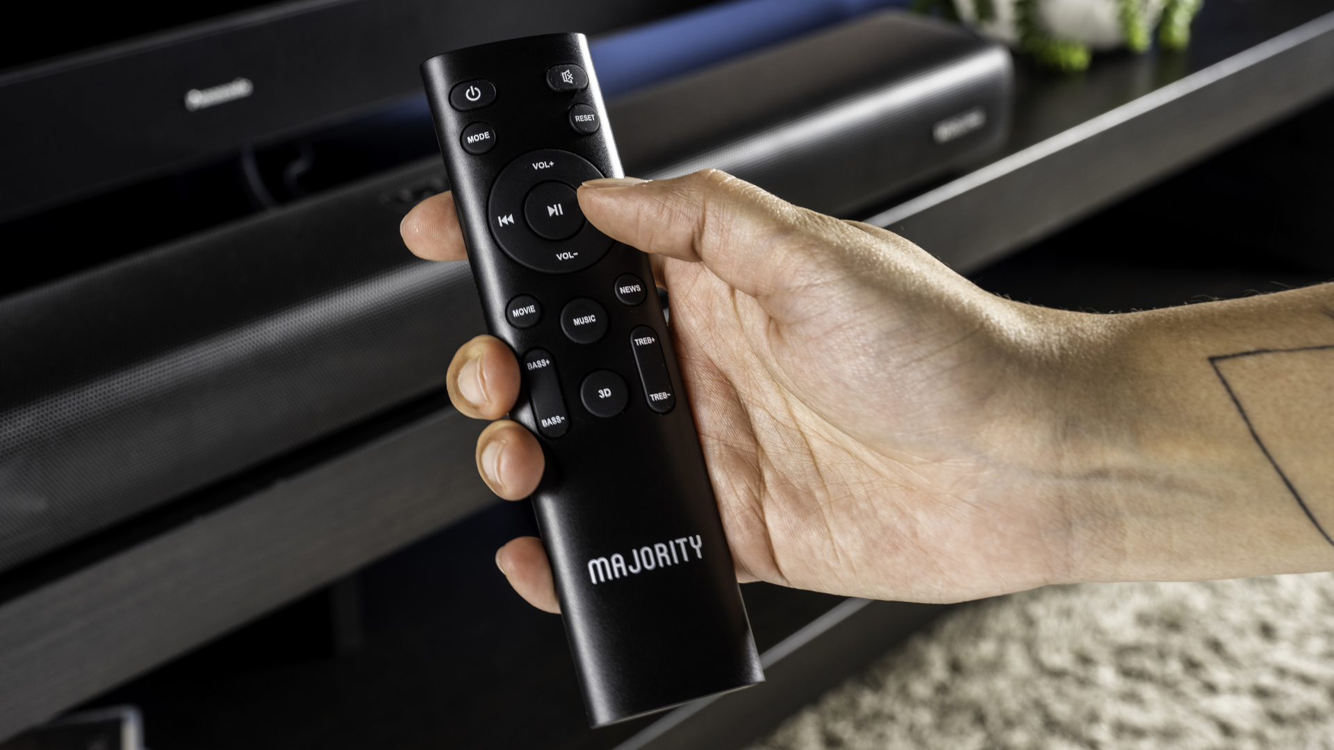 majority elias, a black soundbar with a silver majority logo, and a hdmi earc port and optical port, with a black remote, photographed on a black TV stand