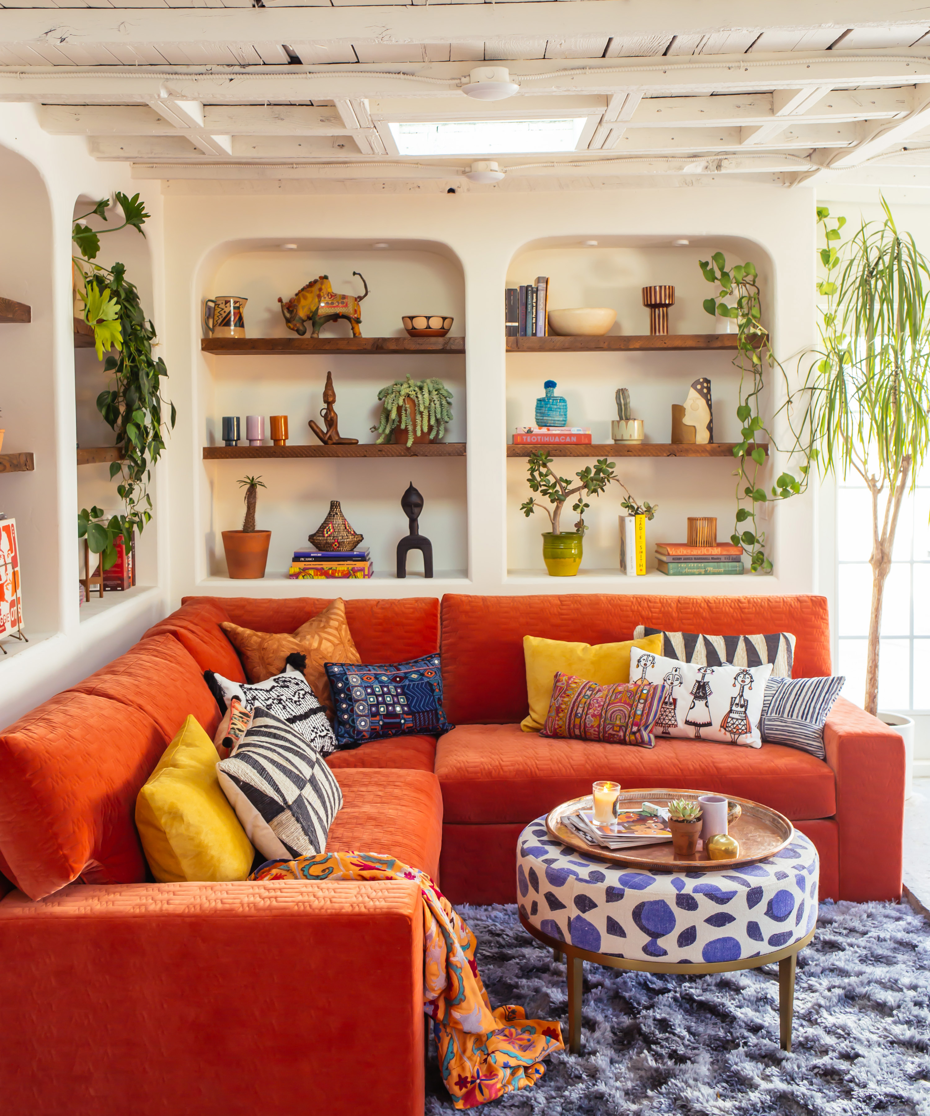 living room with orange sofa and collection of vessels on a bookshelf