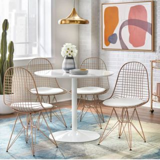 Target dining room with small white table, gold chairs, and a boho rug