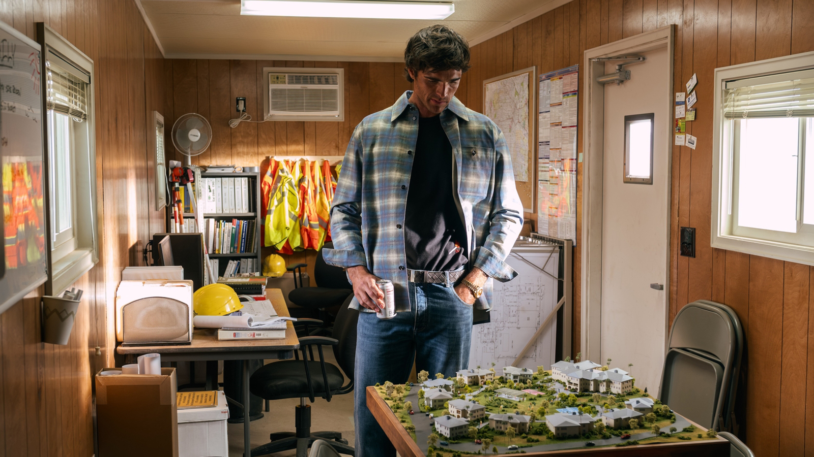 Nate looking down a scale model while holding a cup in Euphoria season 3