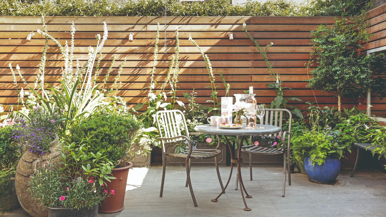 A patio with a garden furniture set and a cedar privacy screen