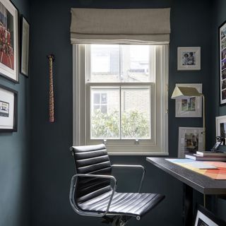 Home office with dark wood desk and leather chair next to window.