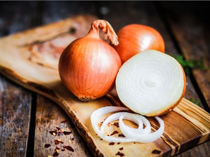Whole And Cut Onions On Cutting Board