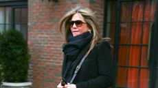 Jennifer Aniston wearing black coat, oversized scarf and sunglasses 