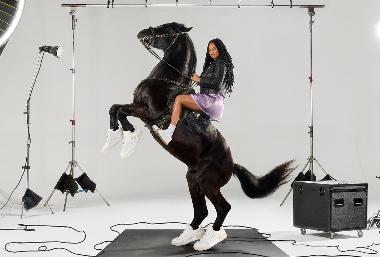 Women's basketball player Satou Sabally from the WNBA's Phoenix Mercury sits atop a black horse wearing Coach's new SoHo Sneakers in a campaign.
