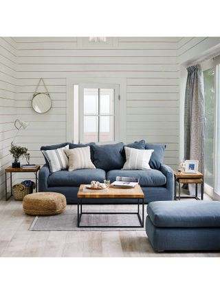 Coastal inspired living room with white shiplap wall paneling and denim blue upholstered sofa