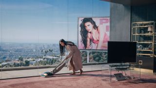 Demi Moore vacuums in front of a Margaret Qualley billboard in The Substance