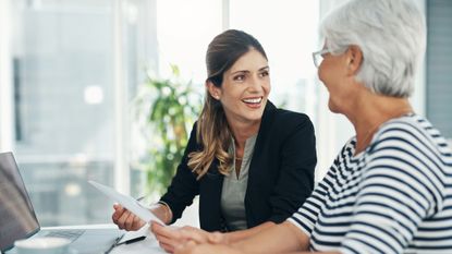 A female professional meets with an older woman. They are going over legal or financial documents for estate planning, retirement planning or other matters.