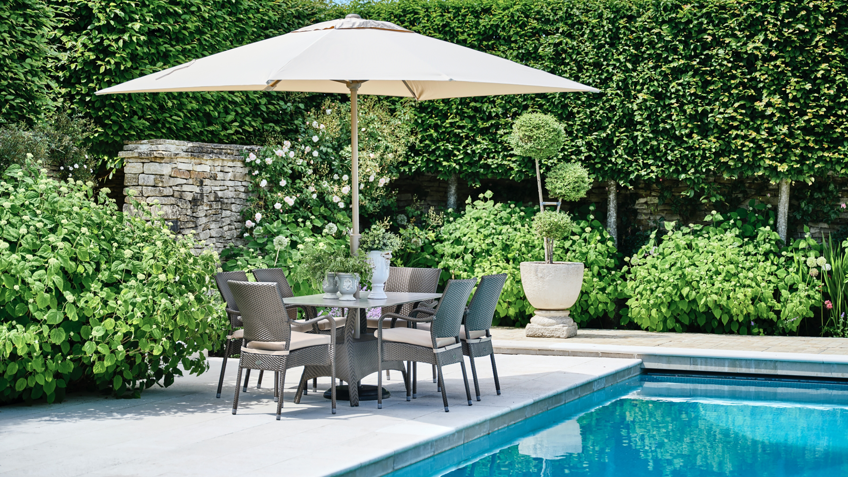 swimming pool with paved surround and large umbrella