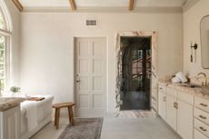 A bathroom with limeash walls, marble bathtub and a muted palette