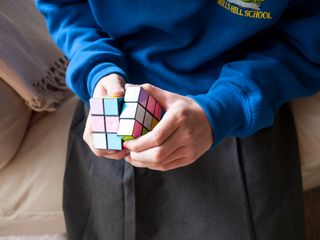 Child in school uniform playing with a Rubik's Cube