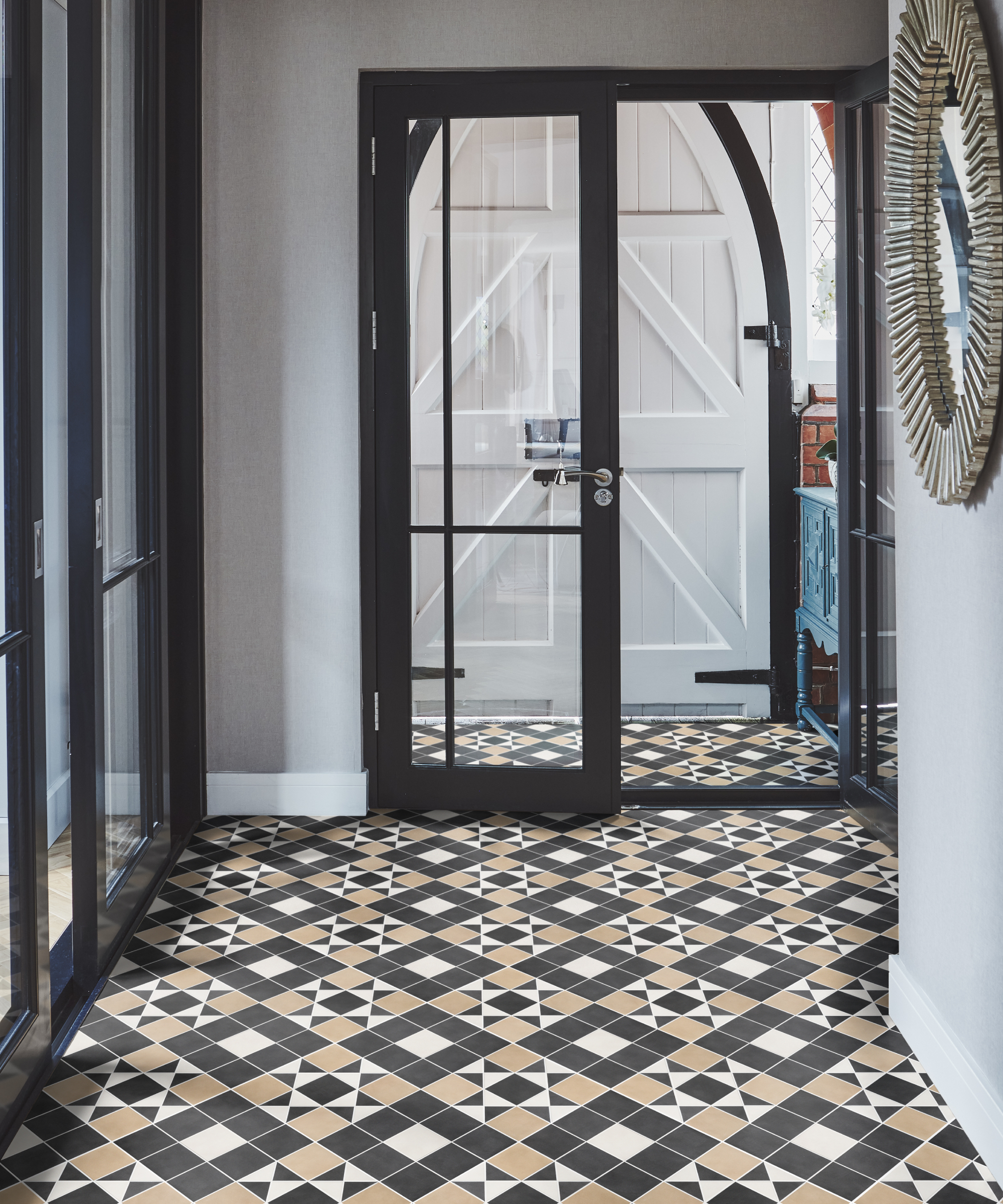 hallway with black, white and light terracotta coloured patterned hallway floor with glass doors leading to arched wooden white front door