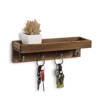 A rectangular dark wood wall hook with keys hanging off it and a succulent plant on top of it