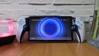 En PlayStation Portal står på ett skrivbord, lutad mot en vit tegelvägg.