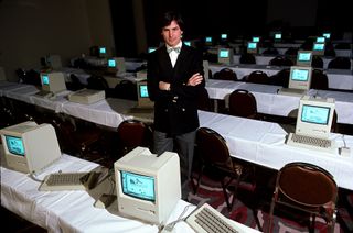 Steve Jobs standing amidst some Apple computers.