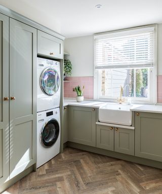 A utility room with light green cabinetry and stacked washing machines