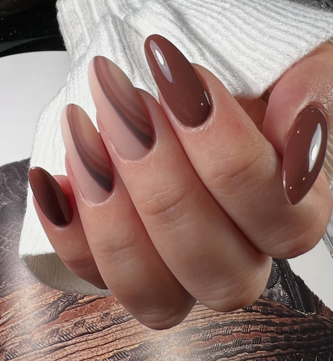 Close-up photo of a person&amp;rsquo;s hand showcasing several shades of brown painted on almond-shaped nails.