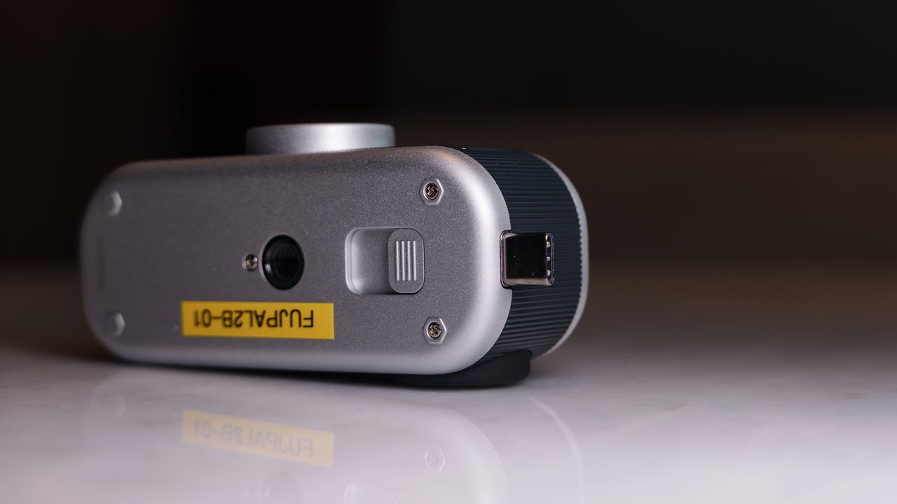 Fujifilm Instax Pal 2 digital camera on a marbled white surface, close up of the USB-C which is extended