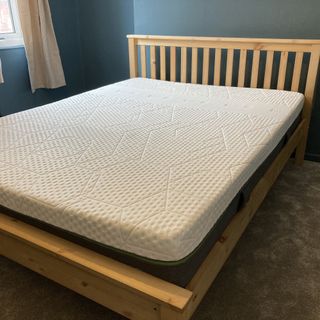 White mattress set-up on a wooden bed frame in a blue walled room