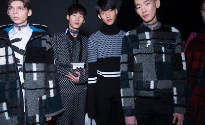 4 male models in dark clothing pose for the camera