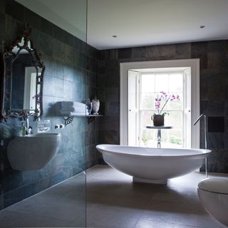 Black and white bathroom with large white window and free-standing bath