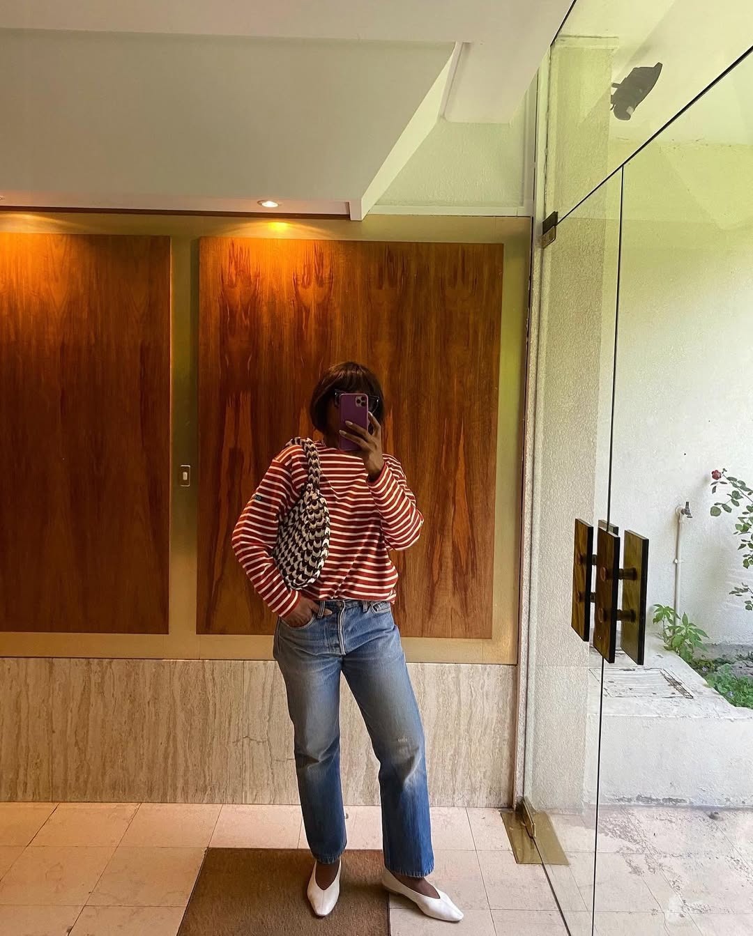 Influencer @frannfyne wears a pair of blue straight leg jeans, white ballet flats, and a striped long sleeve blouse.