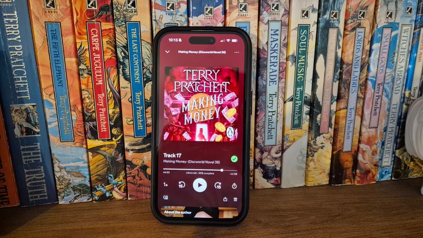 Spotify on iPhone playing Discworld audiobook against a background of Discworld books