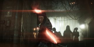 a person in a black cloak wields two laser sword weapons