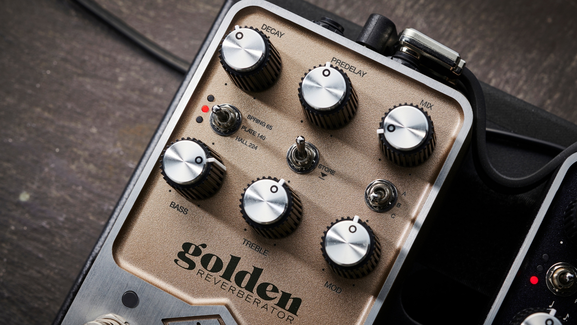 Close up of the controls on a Universal Audio UAFX Golden Reverberator reverb pedal, lying on a wooden floor