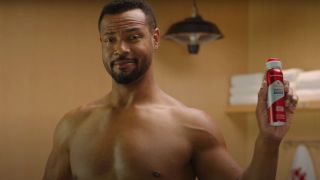 Isaiah Mustafa holding a bottle shirtless in the locker room for Old Spice.