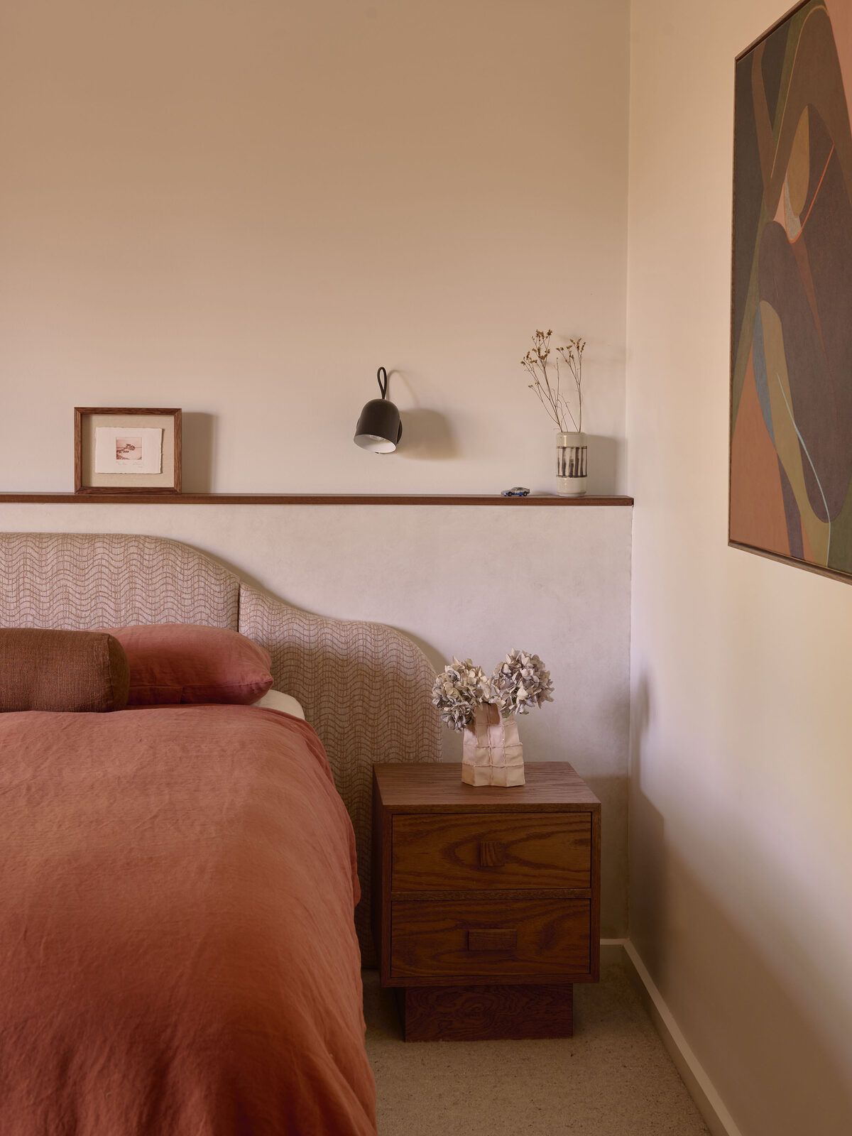 pink and terracotta bedroom with curved bed head and warm-wood accents