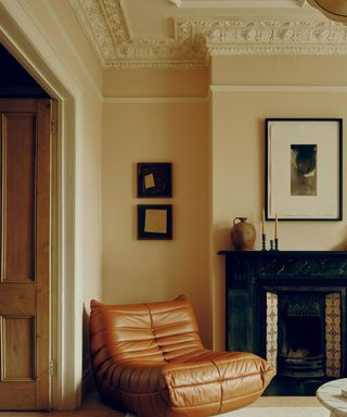 neutral living room with traditional moldings, tan leather chair and black fireplace