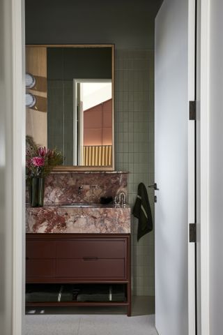 A small bathroom with green wall tiles