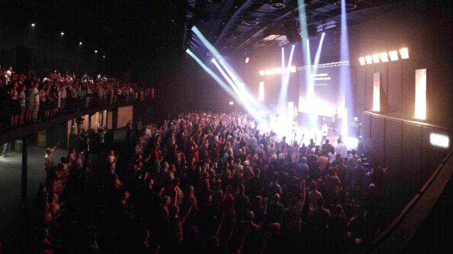 Bright white beams shine down on stage at a house of worship.