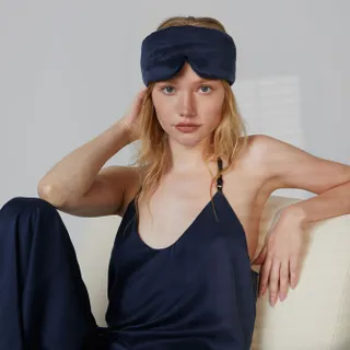 A model wears a silk navy blue PJ set and matching sleep mask.