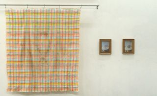 Dirty, hand-painted tablecloth hanging beside two small framed images