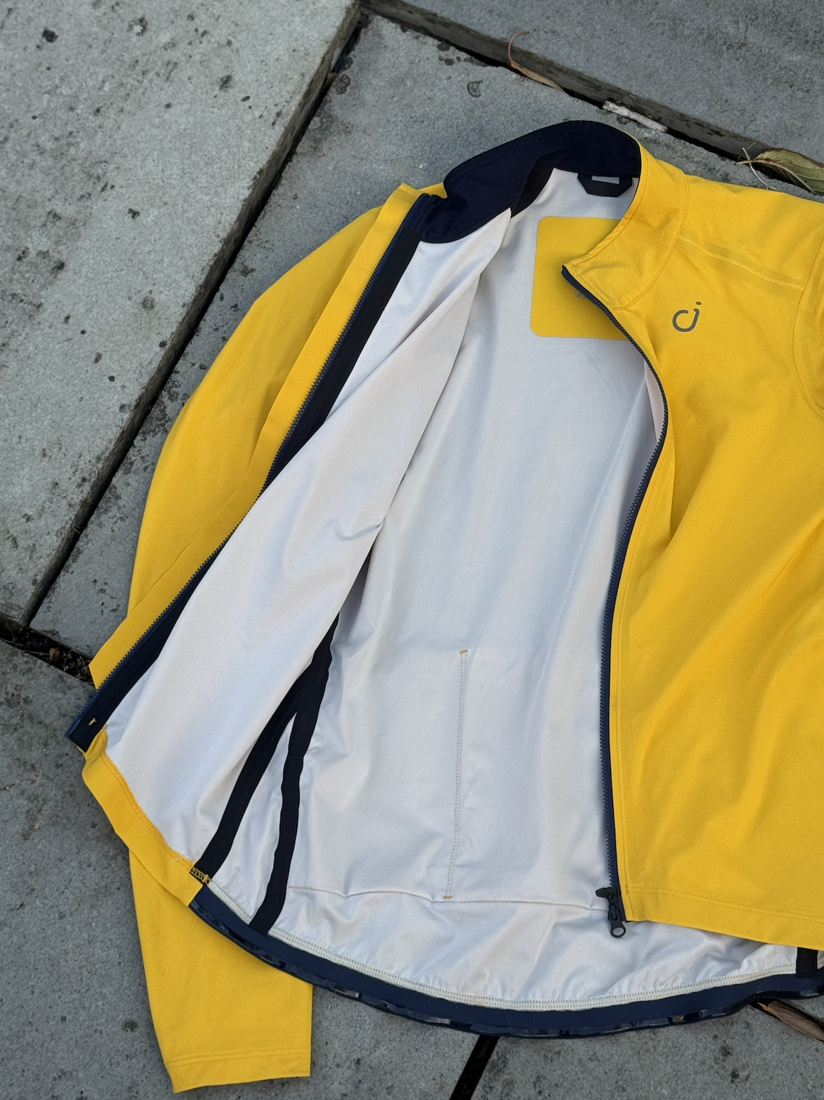 A yellow jacket is open on the ground where you can see taped seams in blue