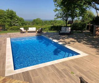 A smart rectangular pool design with a composite decking surrounf and rattan garden furniture to lounge on