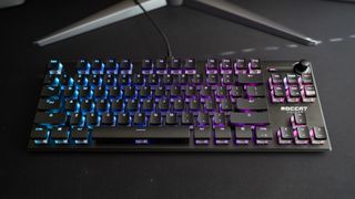 Ett Roccat Vulcan TKL Pro-tangentbord ligger på ett svart skrivbord och lyser i olika RGB-färger.