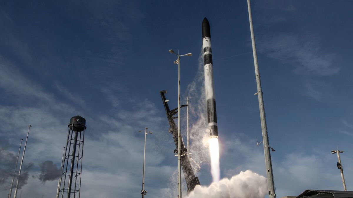 un cohete blanco y negro despega sobre un cono de fuego y humo, luego dos una torre de agua negra