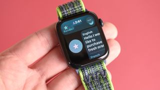 Close-up photo of an Apple Watch SE 2022 against a red background with the new Translate app displayed on the screen