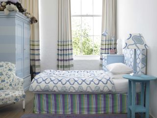 young teen bedroom with blue stripes and graphic prints, blue chest of drawers, blue side table, blue lamps, blue stripe wardrobe