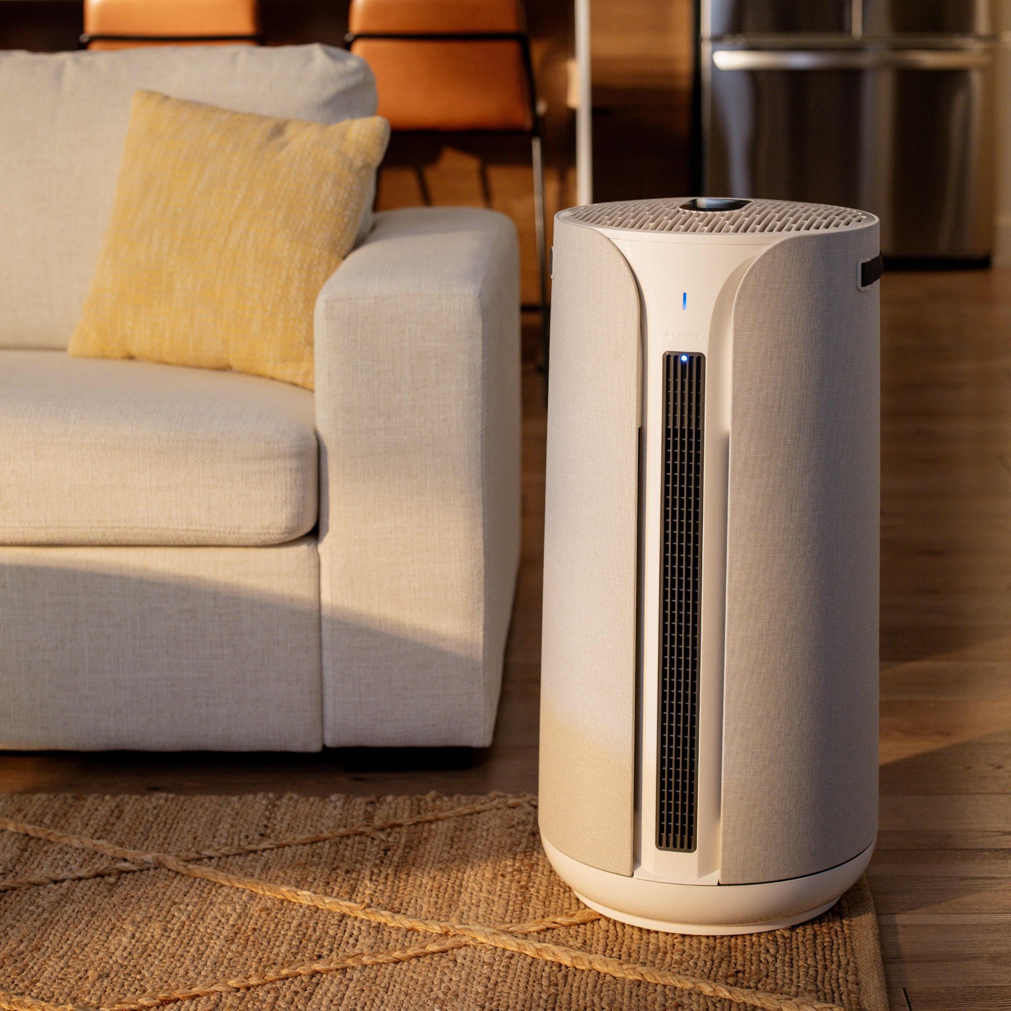 Blueair 3-in-1 air purifier sitting on the floor in a living room, next to a grey sofa