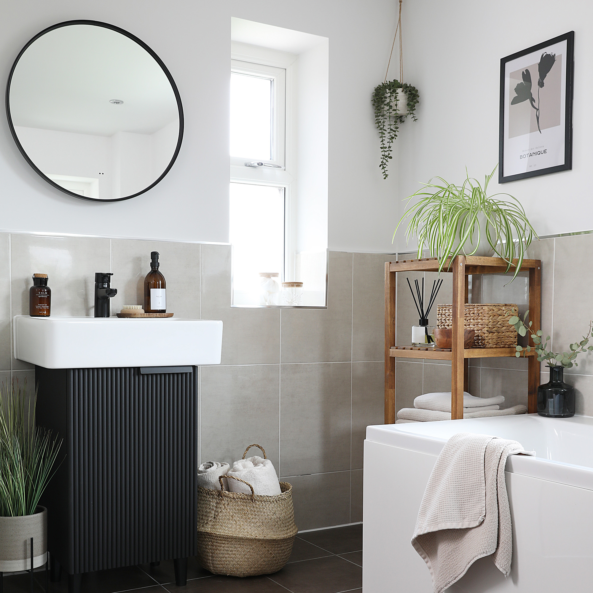 modern bathroom with white walls and grey tiling to the middle of the wall a white sink and black ribbed cabinet underneath